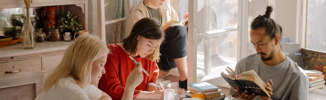 Two individuals sitting together - a woman wearing a vibrant red long sleeve shirt and a young boy in a gray and white plaid shirt - embodying the five essential qualities of a good roommate: respect, kindness, cleanliness, communication, and reliability.